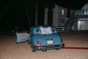 Vintage blue getaway car decorated with 'Just Married' sign at night.