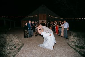 Wedding celebration scene with couple and guests under string lights at night.