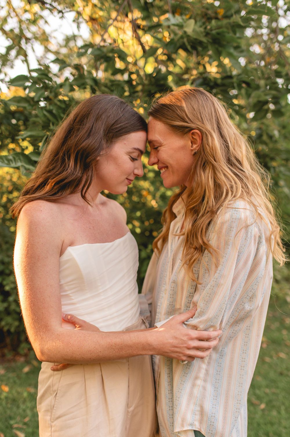 An intimate romantic moment captured outdoors with golden sunlight filtering through autumn leaves in the background.