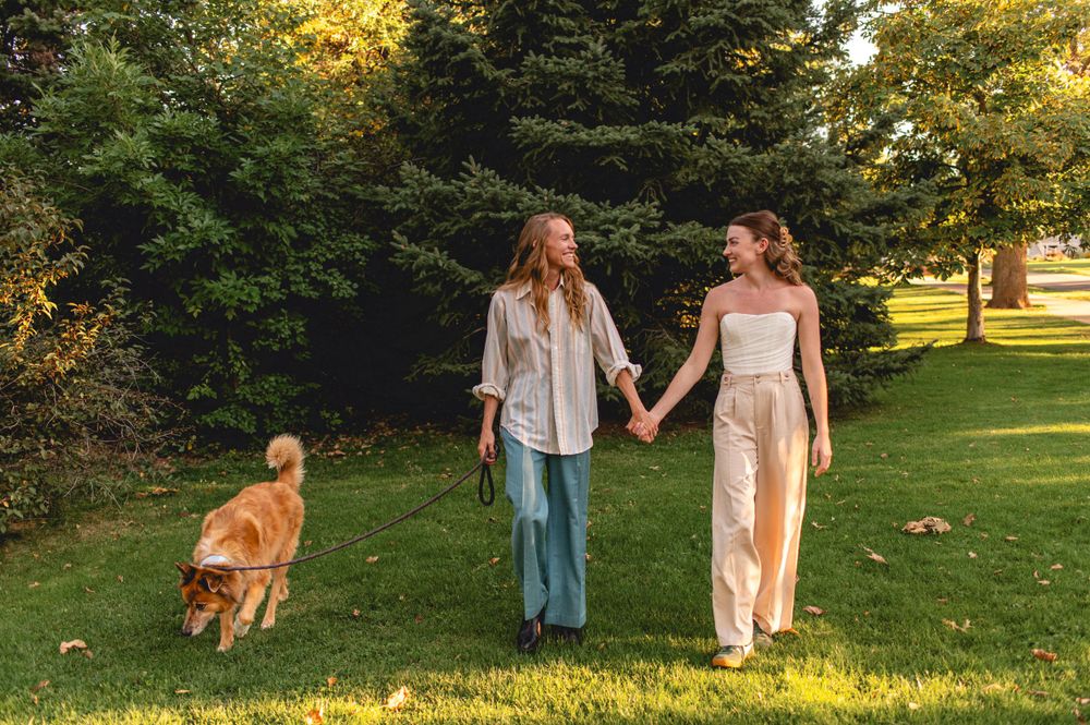 Walking together on grass with a brown dog during golden hour in a peaceful park setting.