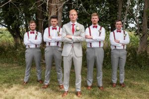 A groom and his groomsman posing with their arms crossed and making serious faces.