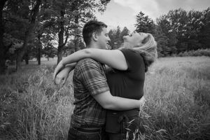 A couple hugging and laughing. The woman is throwing her head back. The photo is in black and white.