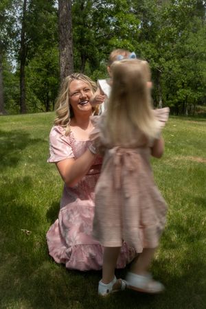 A mom smiling while looking at her daughter who is facing away from the camera.