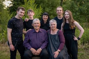 Seated grandparents surrounded by 4 grandchildren and their daughter.