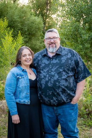 A couple wearing black and denim smiling at the camera.