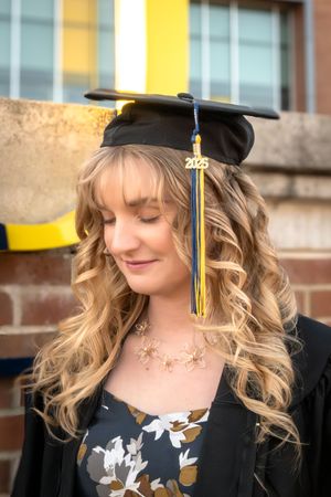 A young woman wearing a graduation cap with a year charm that says "2025"