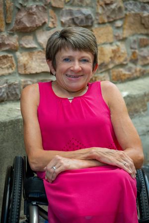 A woman wearing a bright pink dress, sitting in a wheelchair.