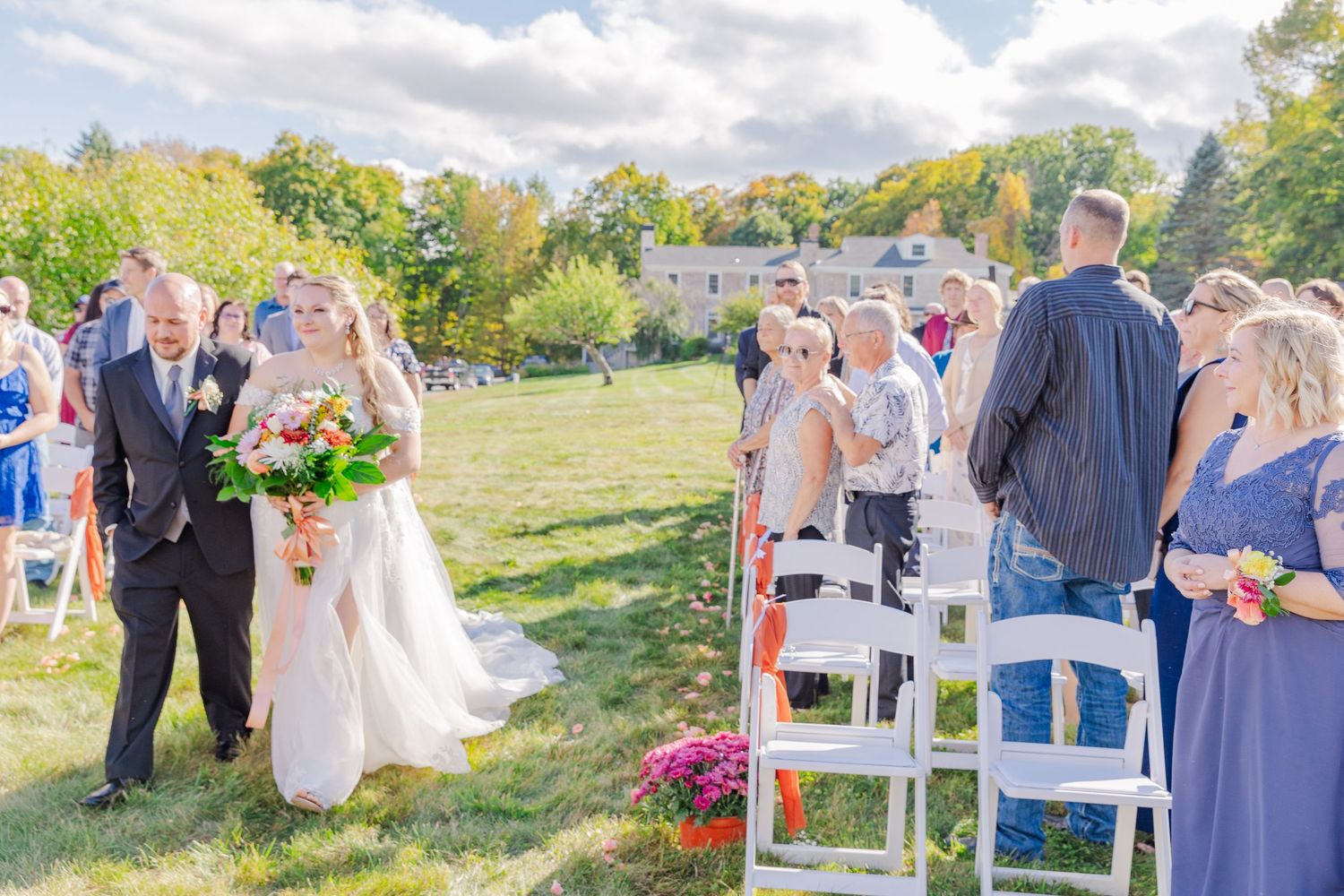 Outdoor wedding ceremony with white chairs and mountain scenery in the background.