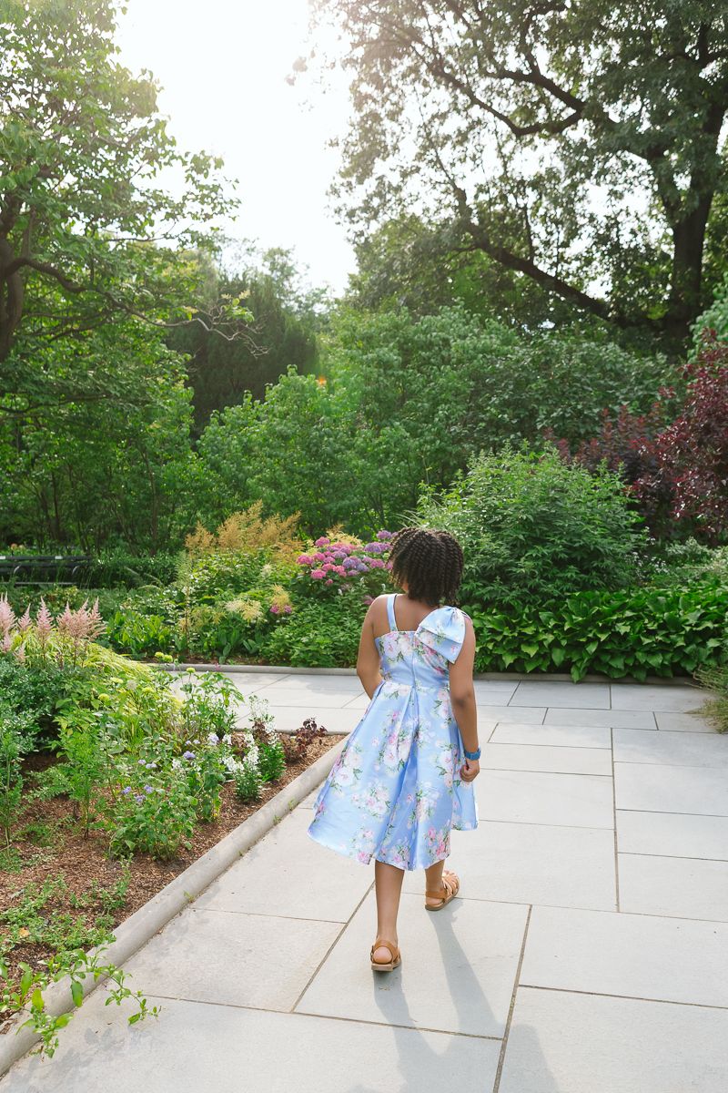 Girl walking to manicured garden in Central Park, captured by NYC family photographer Paula Brearley