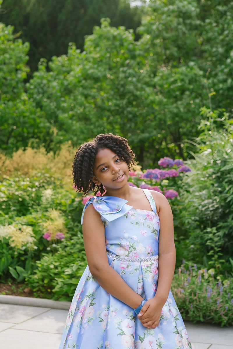 Portrait of girl in blue dress against lush Central Park garden greenery