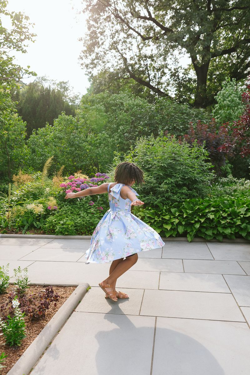 Candid of girl twirling in Central Park garden with beautiful sunlight
