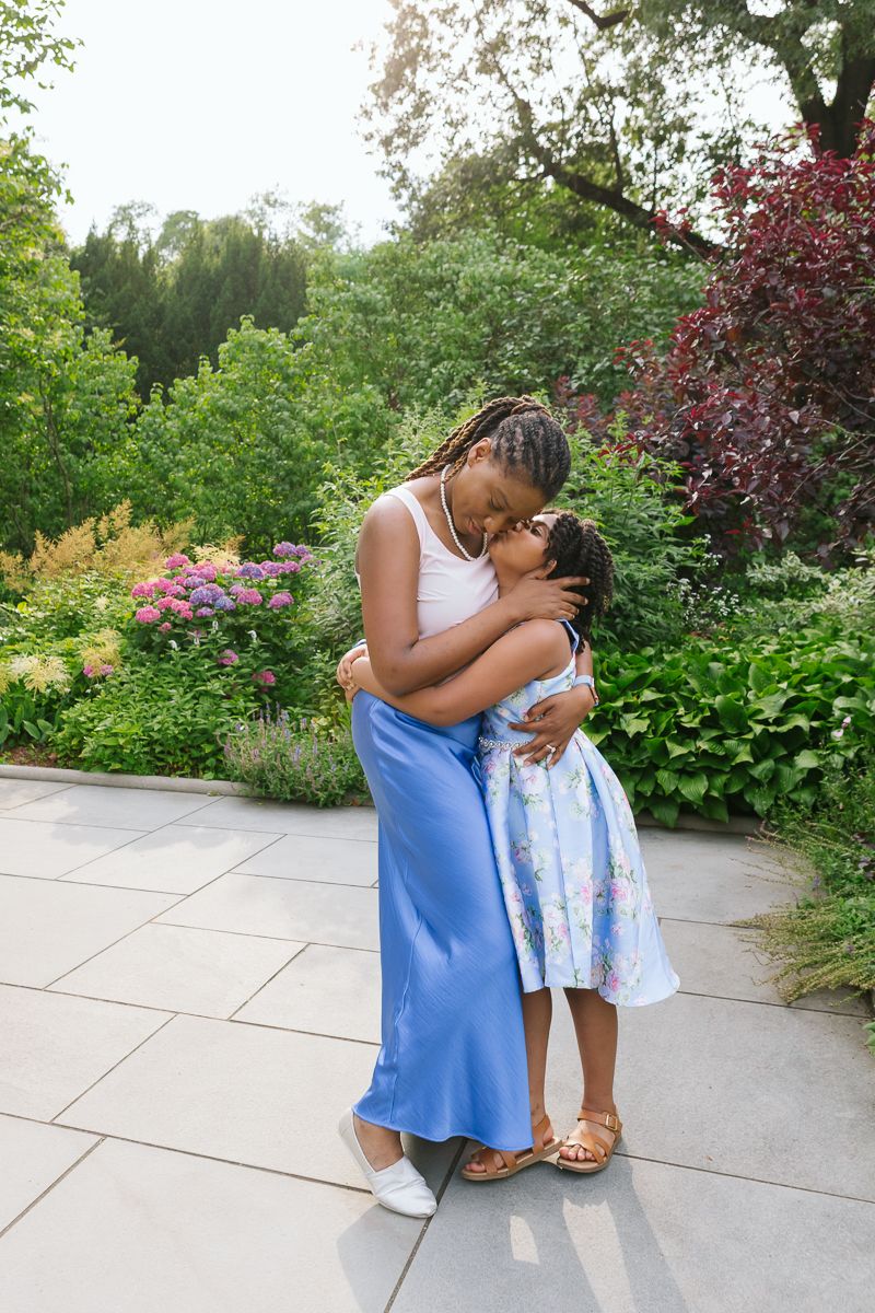 Girl giving her mom a hug and kiss, captured in Central Park NYC