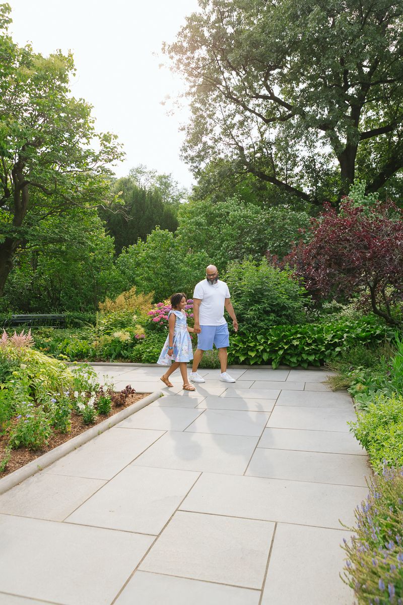Girl strolling garden with dad during NYC family session by Paula Brearley
