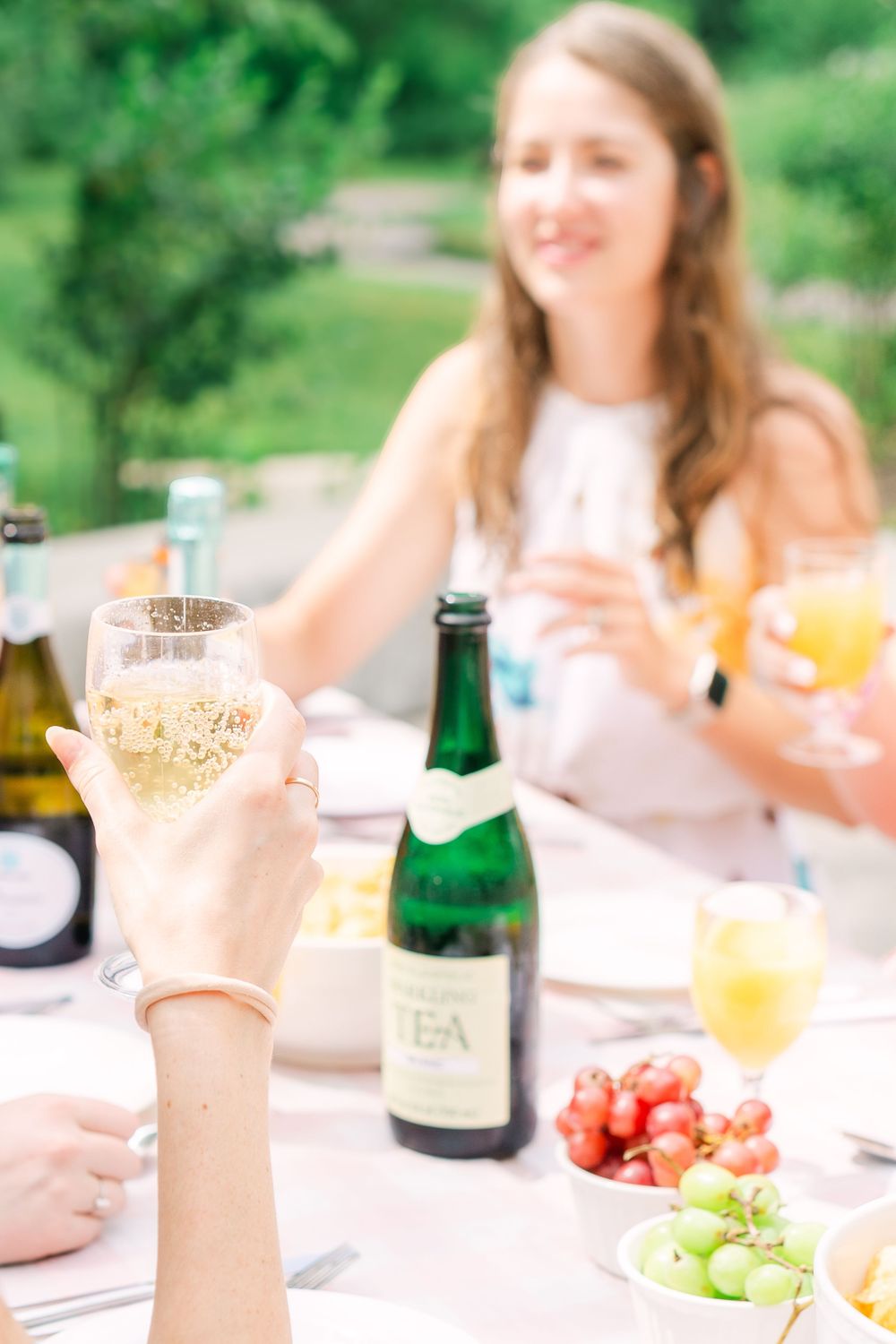 Candid moment of smiling girls seated at a table, their glasses catching the light as they enjoy doughnuts and fresh fruit at a brunch