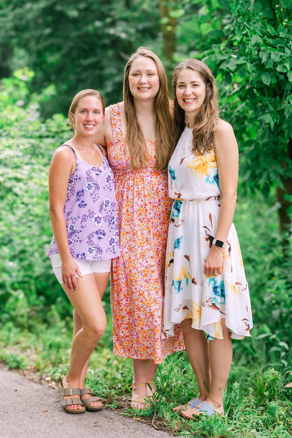 Bride-to-be smiling warmly alongside her friends with lush flowers and greenery in a countryside setting in Victoria, Minnesota