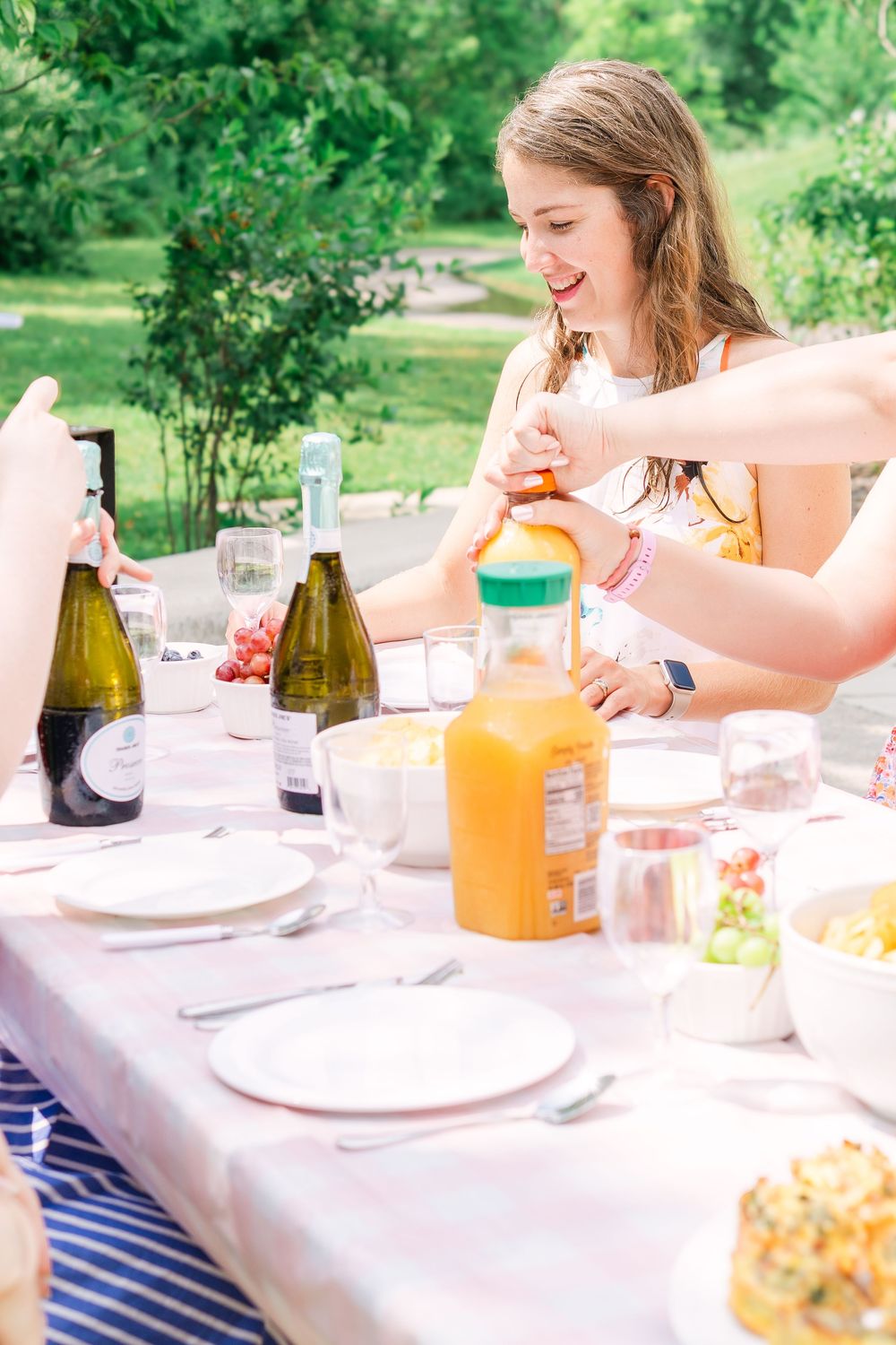 Candid moment of smiling girls seated at a table, their glasses catching the light as they enjoy fresh brunch in Victoria, MN Bachelorette
