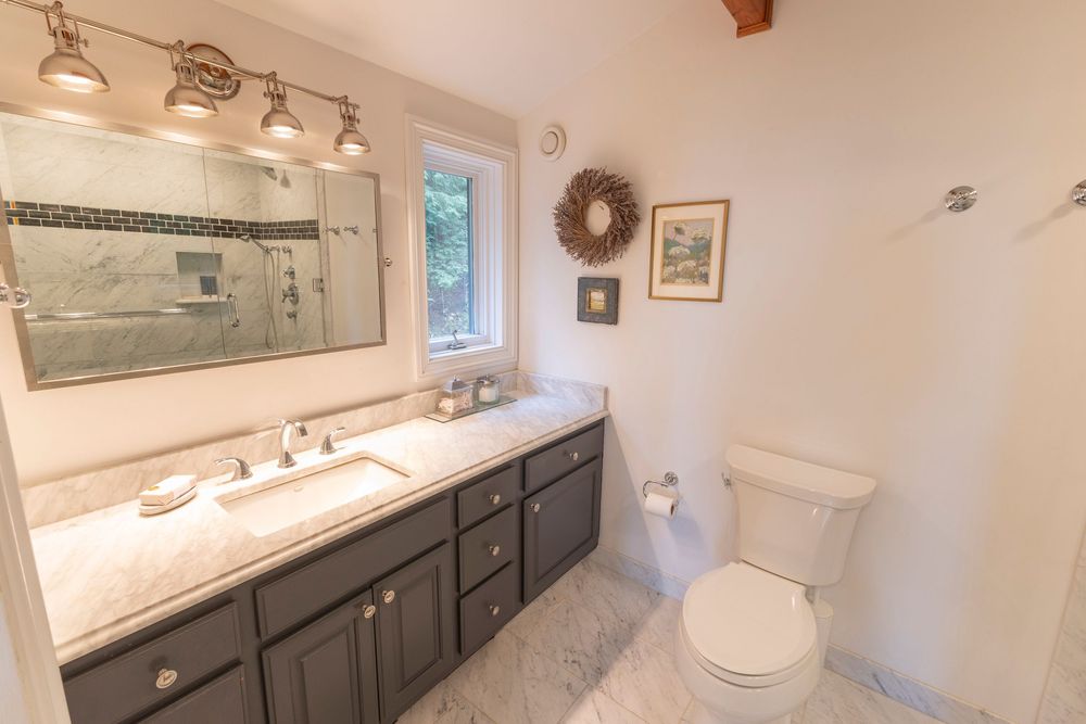 Modern bathroom with white vanity and track lighting displayed from various angles.