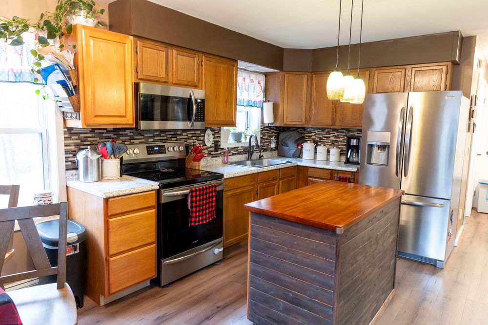 Modern kitchen with wooden cabinets, stainless steel appliances, and center island with butcher block top.
