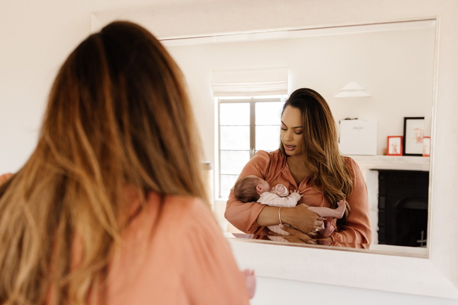 A mom holds her newborn baby in front of a mirror during her in-home newborn session with Cindy Tucey Photography