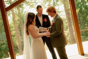 A couple exchanges vows during an intimate wedding ceremony in a sunlit glass chapel.