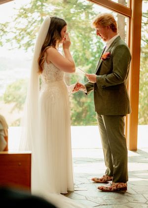 An emotional exchange of vows between a couple in a glass-walled venue with natural light.
