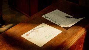 Close-up shots of wedding documents and paperwork on wooden surfaces.