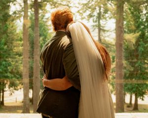 Outdoor wedding photography amongst tall evergreen trees in golden sunlight.