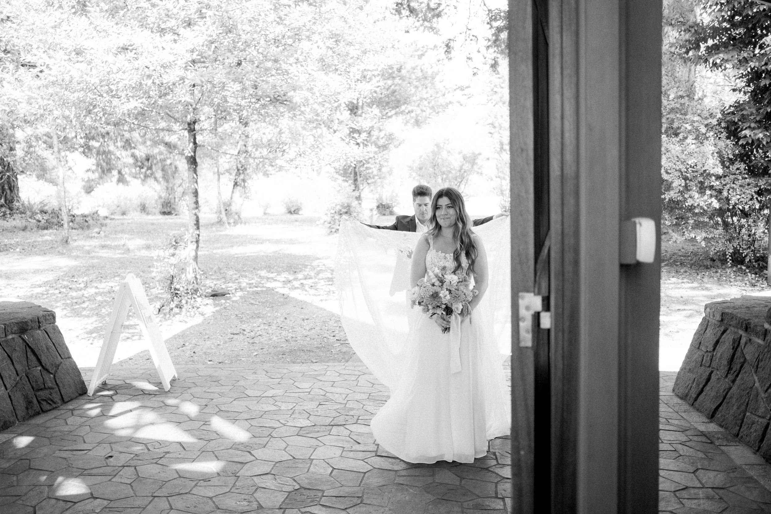 Black and white wedding photos captured through doorways and forest settings.