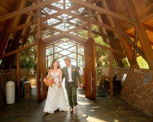 A wedding couple walks through a stunning architectural chapel filled with natural light.