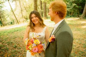 A joyful wedding moment captured in warm sunlight on a wooded path.