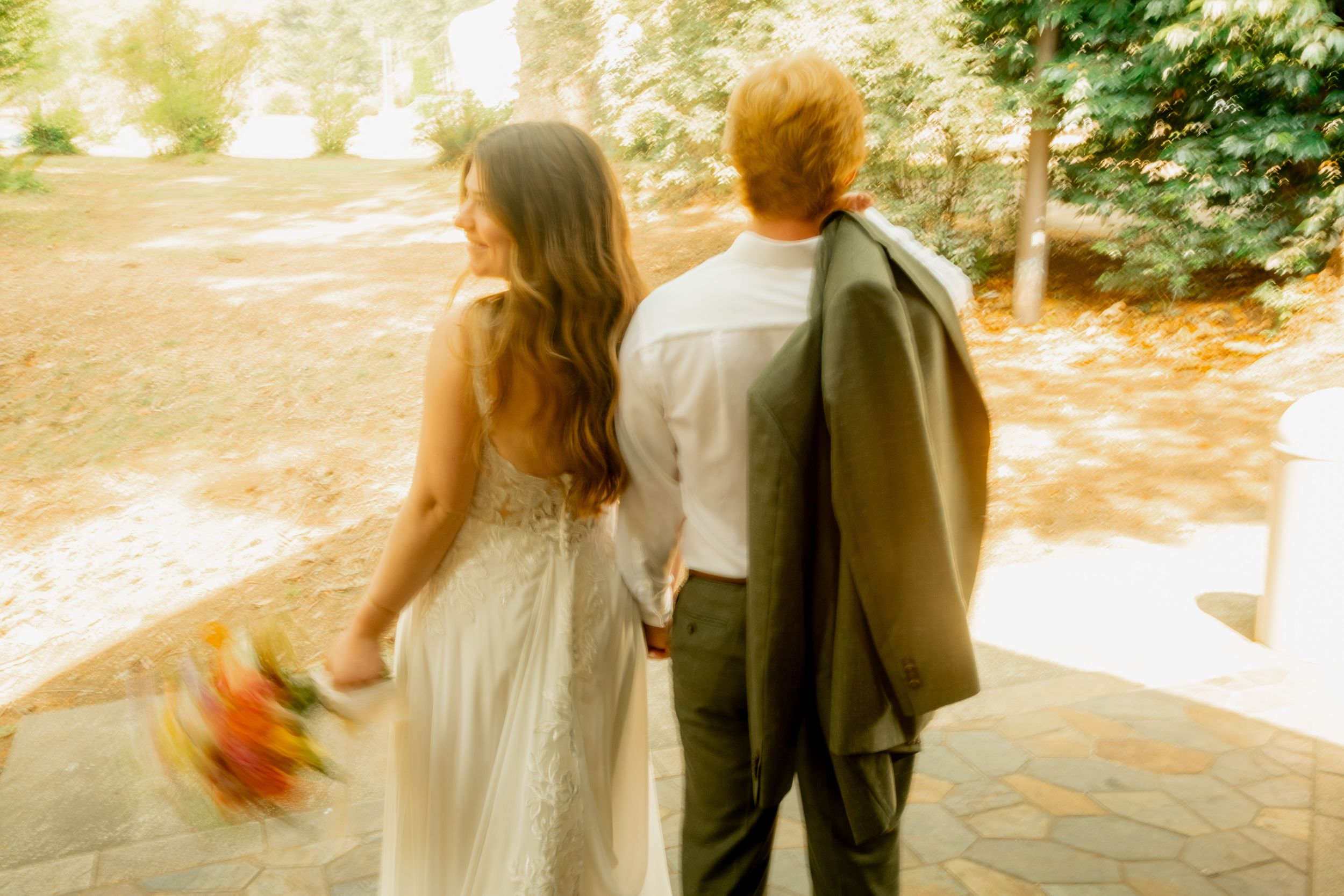 A couple walking together through an autumn forest path with golden sunlight filtering through the trees.