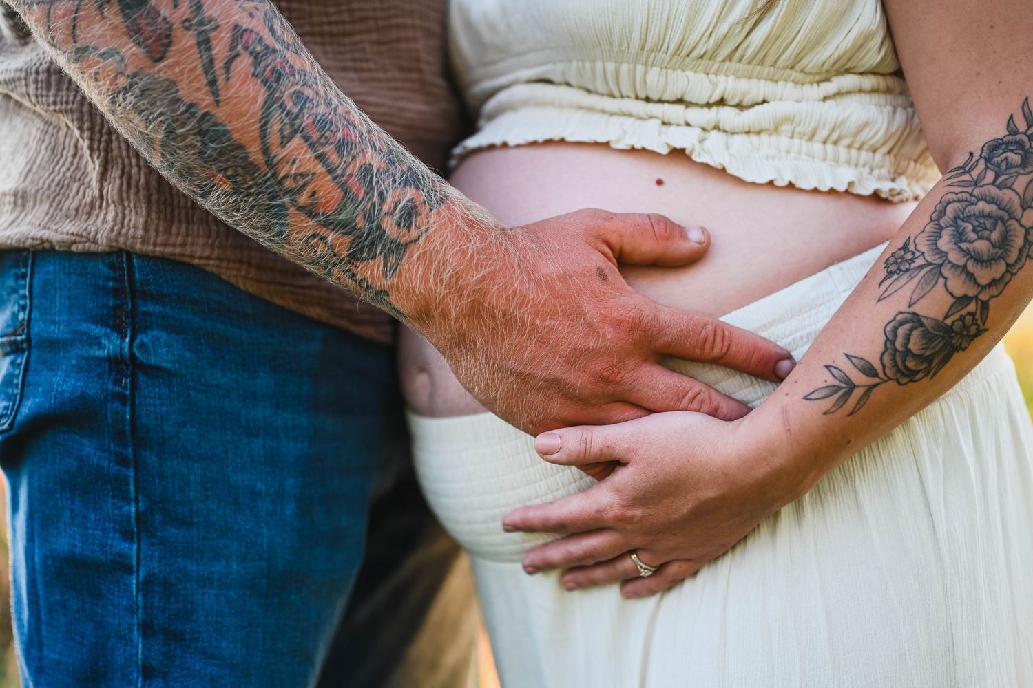 Dad holds mom to be during maternity photo session with K. Manchuck Photography, tattoos on both mom and dad's arms