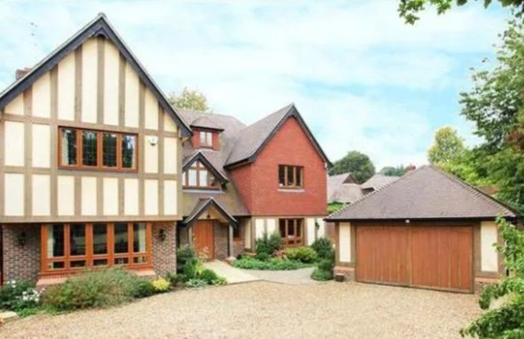 Modern Tudor-style brick and timber residential building with gravel driveway and landscaped grounds.