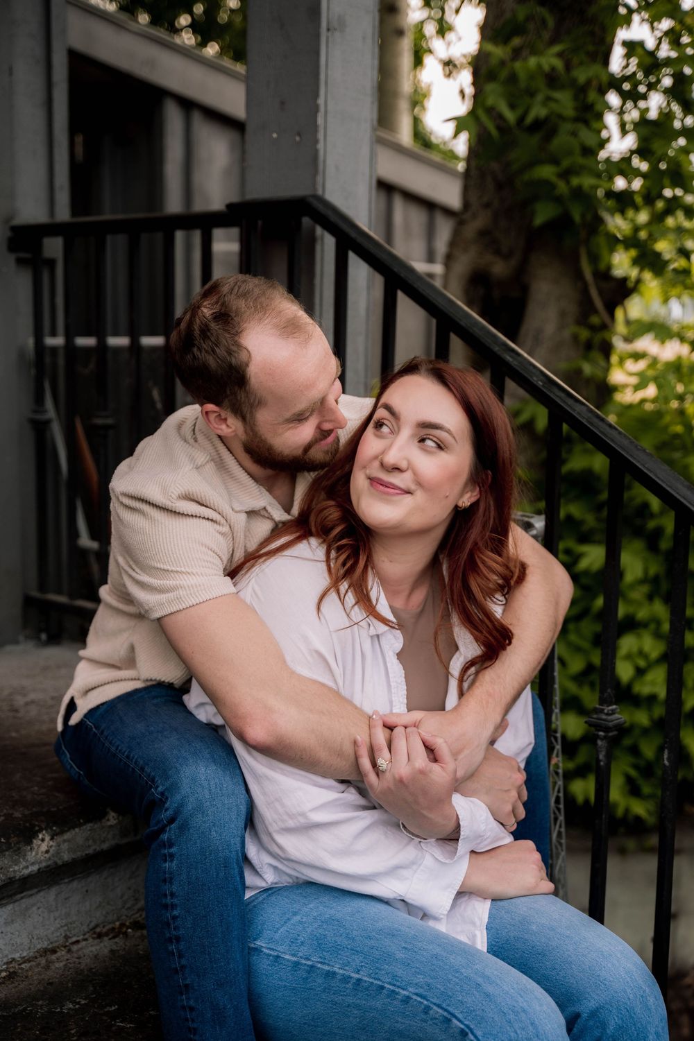 Romantic moment between a couple sitting together on outdoor steps by a gray building.
