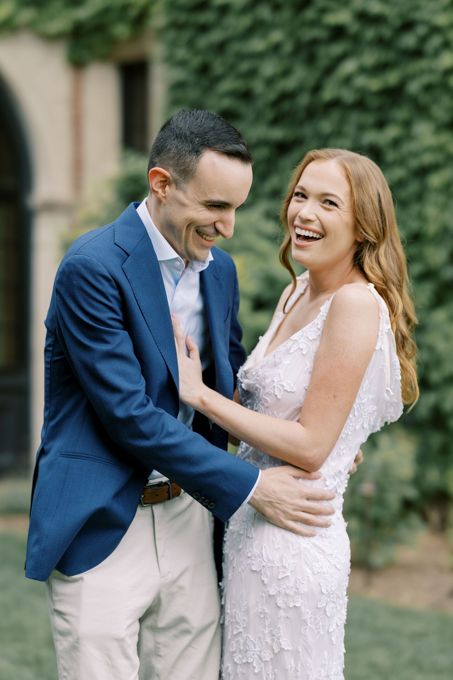 Newlywed couple shares candid laughing moments in series of romantic portraits outdoors with greenery backdrop at Pendry Natirar in Peapack.