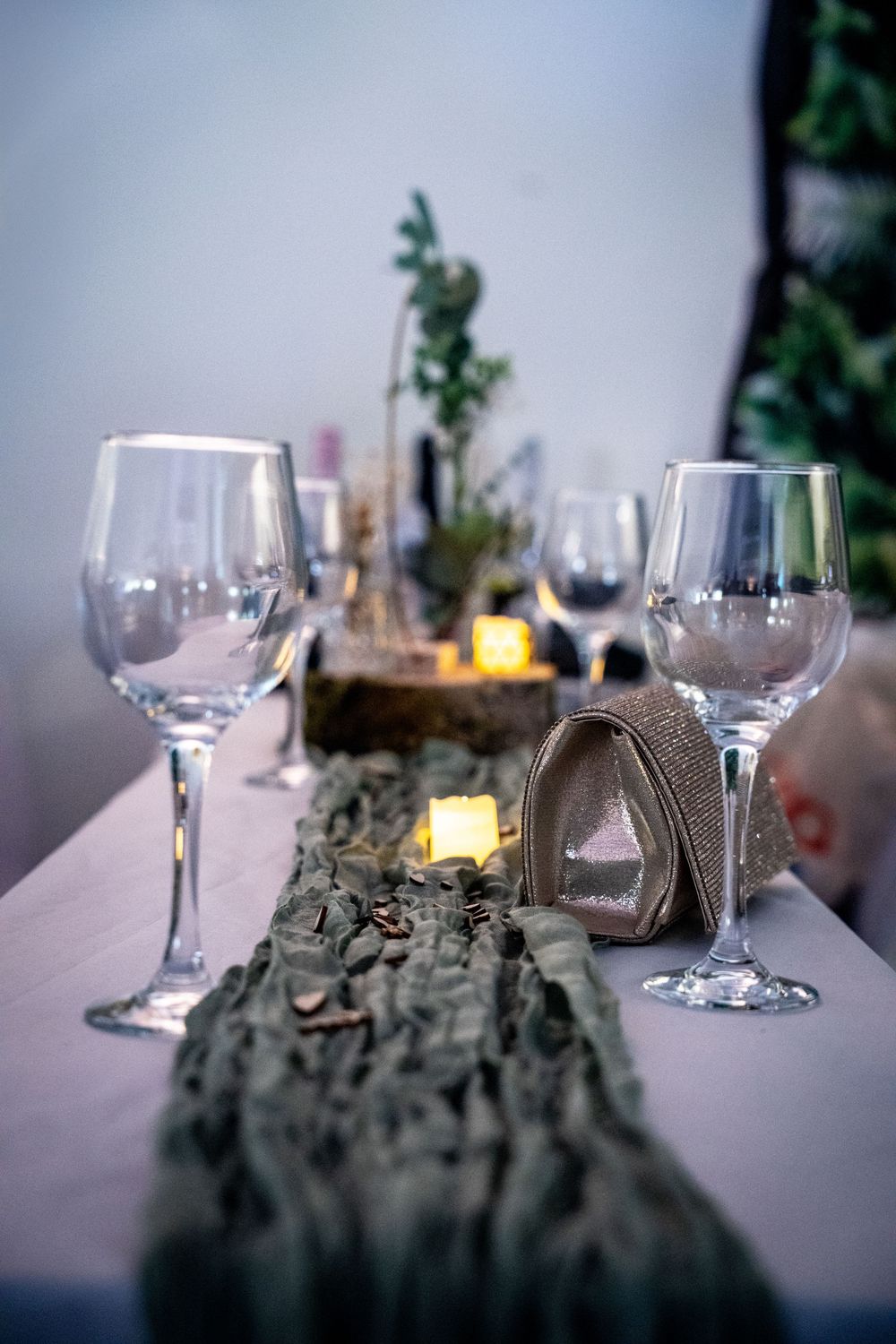 Wine glasses sit alongside decorative candles and earthy table decor creating an elegant tablescape setting.