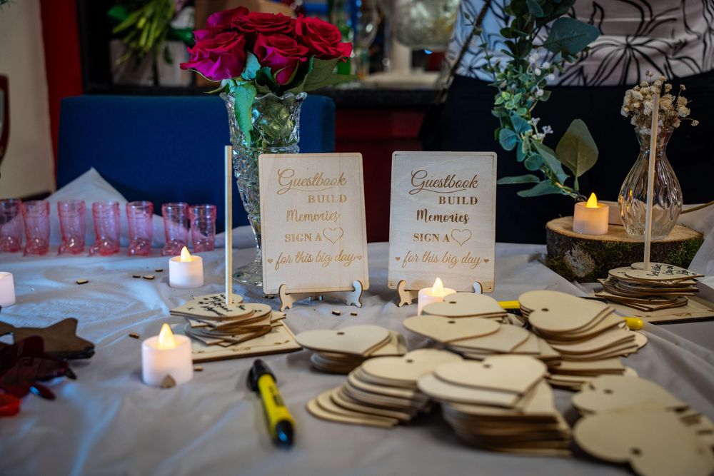 Wedding guest book table setup with wooden hearts and candles next to framed messages at reception.