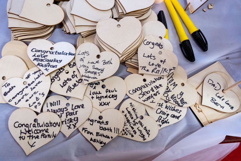Wooden heart shaped gift tags with handwritten messages scattered on a white background.