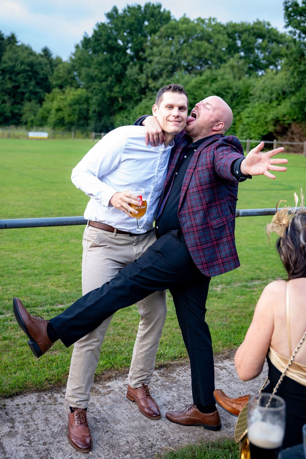 A sequence of four photos showing two people playfully falling over on a grassy field.