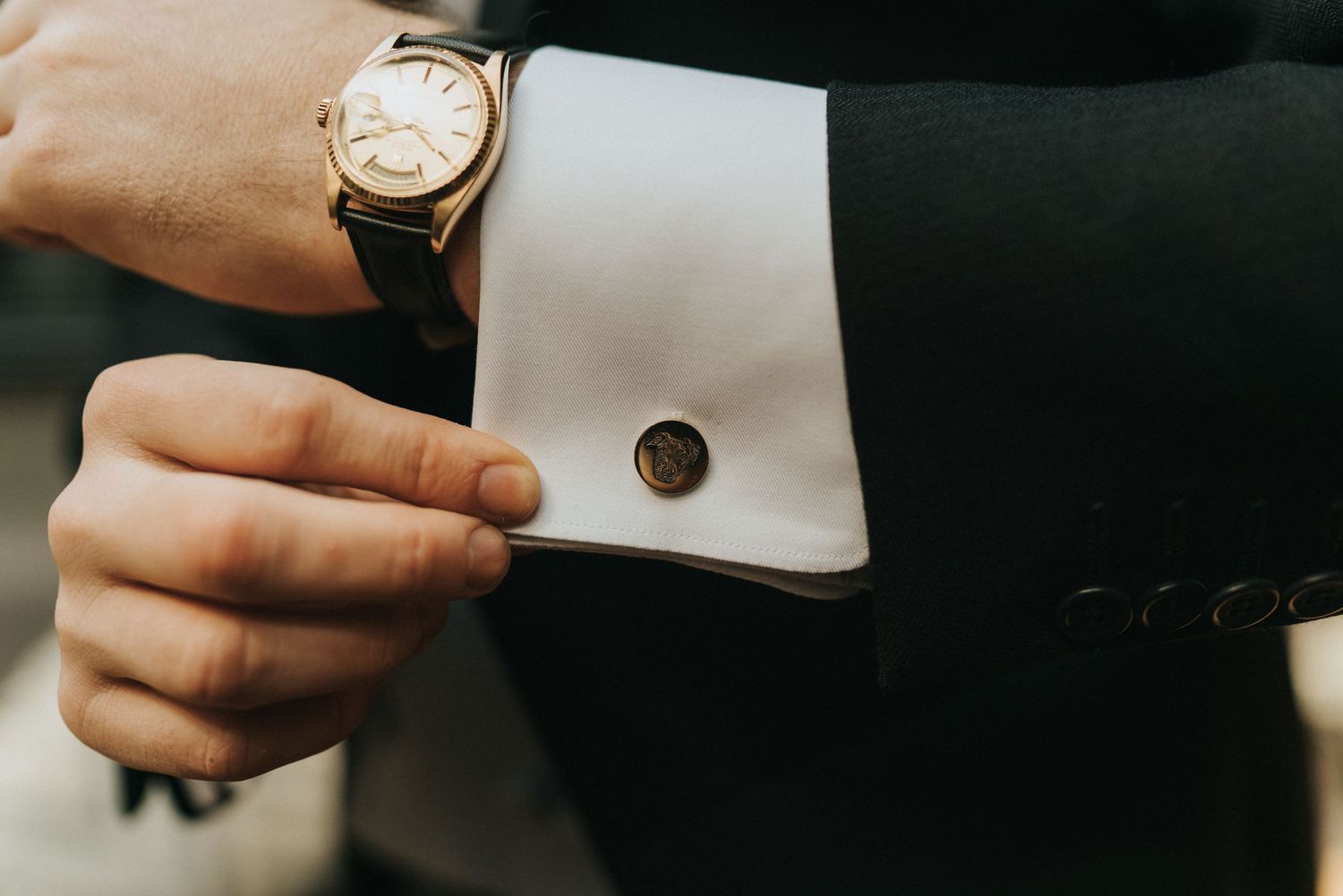 Close-up view of hands adjusting white cufflinks during formal dress preparation.