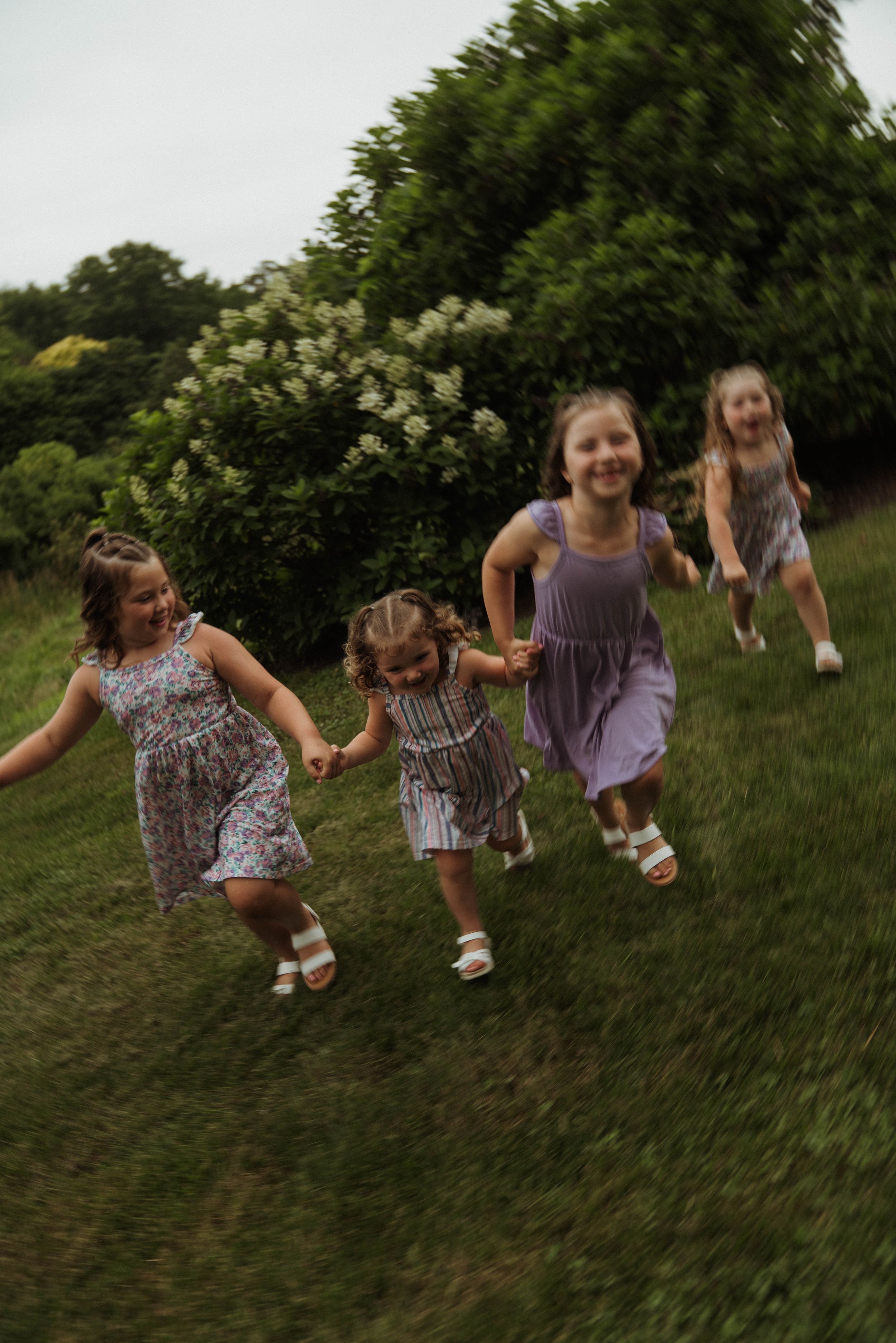 Group of children playing and running together in a grassy outdoor setting wearing coordinated purple outfits.