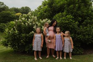 Casual outdoor family photo session with coordinated outfits against natural greenery.