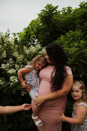 Candid family moment captured outdoors with loving embraces and natural expressions.