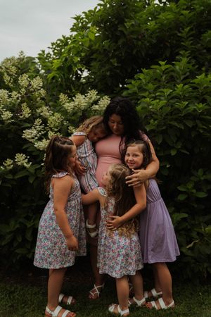 Intimate family group hug captured in natural outdoor setting with lush background.