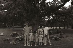 Family members pose together in a grassy outdoor setting during a photo session.