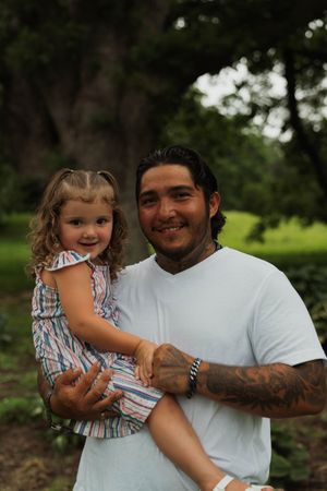 Playful interaction between two people outdoors with one wearing a white t-shirt.