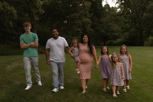 Group photo of people wearing coordinated pastel outfits standing in a grassy field.