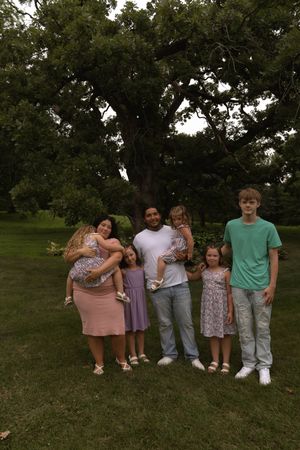 Family group photo with members wearing casual attire standing on grass.
