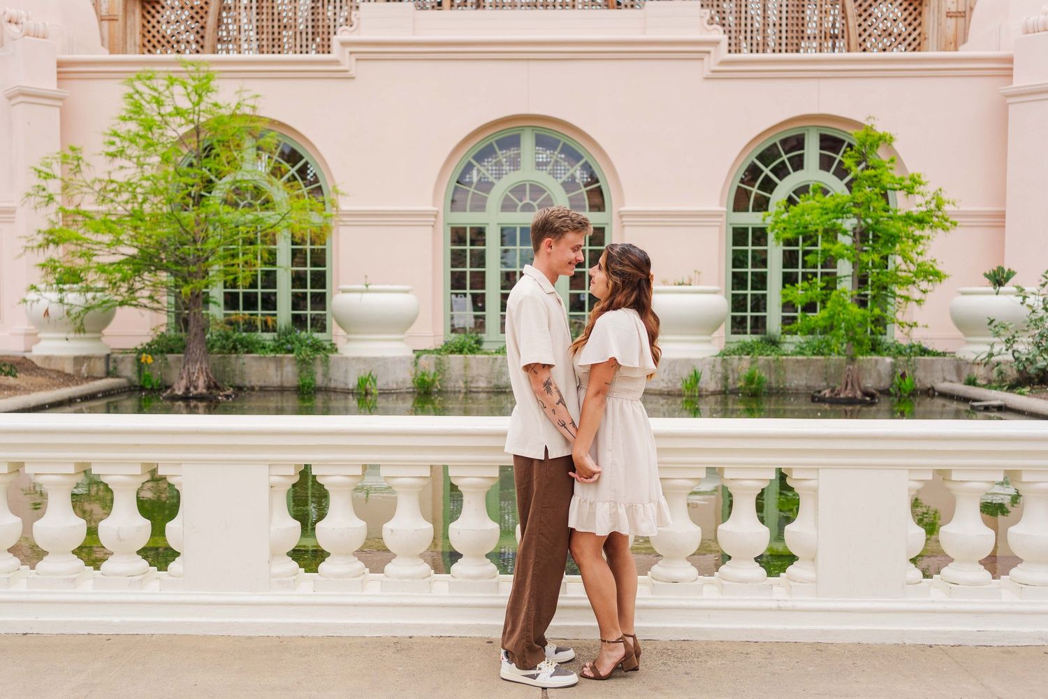 A romantic engagement photoshoot series set on an elegant stone balcony at a historic mansion with ornate architecture.
