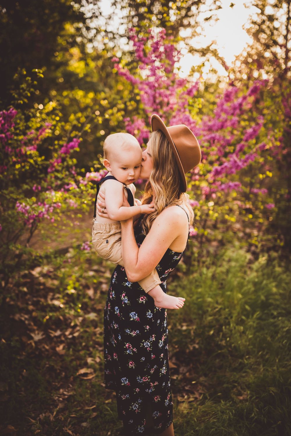 Beautiful spring portrait against blooming pink flowers in warm evening light.